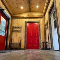 The lodge entry with vaulted wood ceiling, signature red door, and wood-paneled walls