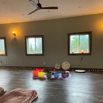 Colored singing bowls arranged on the studio floor under warm sconce lighting