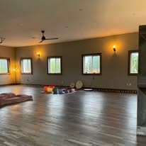 Studio angle showing wall sconces, windows, and meditation cushions center-frame